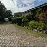 Steinweg führt zu einem Haus mit Grünflächen und Sträuchern.