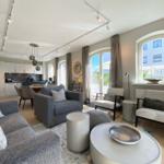 Wohnzimmer mit Sofa, Sitzgelegenheiten und Blick auf Balkon.