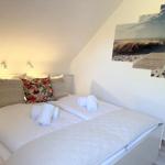 Schlafzimmer mit Doppelbett, dekorativen Kissen und Strandbild an der Wand.