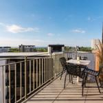 Terrasse mit Tisch und Stühlen, Blick auf Stadt und Meer.