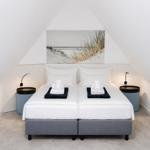 Schlafzimmer mit Doppelbett, zwei Nachttischen und Wandbild