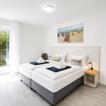 Zimmer mit Doppelbett, Balkon und Wandbild. Nachttisch und Spiegel sind vorhanden.