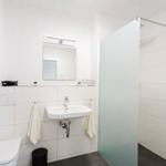 Bathroom with shower, sink, and toilet. White tiles and mirror.