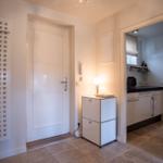 Eingangsbereich mit Tür, Schrank und Blick in die Küche.