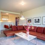Ein Wohnzimmer mit rotem Sofa, marmerartigem Tisch und Wandbildern.