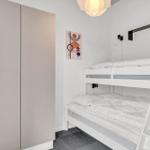 Zimmer mit Doppelstockbett, Kleiderschrank und Wandbild.