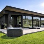 Moderne Villa mit Whirlpool, Terrasse und großem Glasbereich. Grünfläche und klare Sicht.