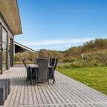 Terrasse mit Tisch und Stühlen neben modernem Haus mit großem Glasbereich.