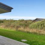 Terrasse mit Blick auf Grasfläche und Büsche. Im Hintergrund ist ein Haus sichtbar.