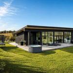 Moderne Villa mit Whirlpool, Terrasse und Trampolin auf grünem Grundstück.
