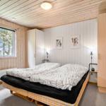 Schlafzimmer mit Doppelbett, Holzwand und Fenster. Hängende Bilder an der Wand.