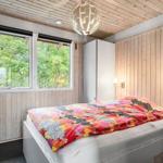 Schlafzimmer mit Bett, Fenster und Holzwandverkleidung.