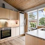 Küche mit Holzdecke, weißen Schränken und Blick auf Garten.