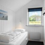 Schlafzimmer mit weißem Bett, Fenster und Wandbild.