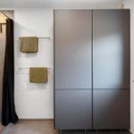Badezimmer mit Dusche, Badewanne, Handtuchhaltern und Fenster mit Pflanzen.