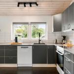 Moderne Küche mit grauen Schränken, Spüle und Fenster zum Garten.