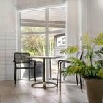 Raum mit Tisch, Stühlen und Pflanze neben Pool und Fenster zur Terrasse