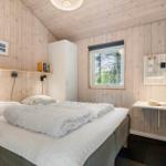 Schlafzimmer mit Bett, Schreibtisch und Fenster. Holzwand und weiße Möbel.