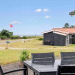 Terrasse mit Tisch und Stühlen, Blick auf Strandhaus und dänische Flagge.