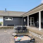 Haus mit Terrasse, Grill, Spielplatz und Tisch mit Stühlen.