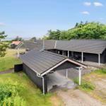 Ein dunkles Haus mit Garage und Terrasse, umgeben von Grünflächen und Bäumen. Der Blick geht zum Meer.