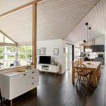 Großes Wohn- und Esszimmer mit Holzdecke, Kamin und moderner Küche.
