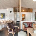 Wohnzimmer mit Essbereich, Sofa, Sessel und Holzdecke. Treppenaufgang zur oberen Etage.