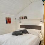 Schlafzimmer mit Bett, Bücherregal und Fenster.
