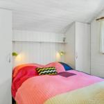 Schlafzimmer mit Bett, weißen Schränken und Fenster. Decke und Wände weiß. Decke mit Holzverkleidung.