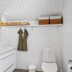 Badezimmer mit Toilette, Waschbecken und Regal mit Körben.