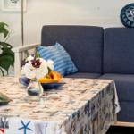 Ein Tisch mit Tischdecke, Blumen und Obst vor einem Sofa mit Kissen.