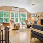Wohnzimmer mit Holzwand, Fenster, Sofa, Sessel und Fernseher.