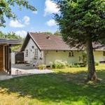 Wohnhaus mit Garten, Terrasse und Holzgarage unter Bäumen.