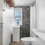 Badezimmer mit Dusche, Waschmaschine und Waschbecken.