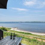 Terrasse mit Tisch und Bierflaschen, Blick auf Strand und See.