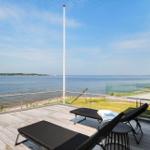 Terrasse mit Liegen und Blick aufs Wasser. Hoher Mast und Glasgeländer.