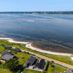 Aerial view of waterfront property with beach, houses, and calm water.