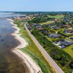 Aerielansicht einer Küstenlandschaft mit Häusern, Strand und Wasser.