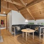 Wohnzimmer mit Holzdecke, Kaminofen, Sofa und Tisch