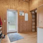 Eingangsbereich mit Holzwand, Tür, Schuhregal und Küchenzeile.