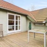 Terrasse mit Holzdecke, Stuhl und Tisch vor einem Haus mit weißen Fenstern und rotem Dach.