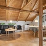 Wohn- und Essbereich mit Holzdecke, Sofa, Tisch und Stühlen.