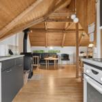 Küche mit Holzdecke, Esstisch und Sofa im Hintergrund.