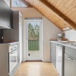Küche mit Holzdecke, Fenster und Tür zum Balkon.