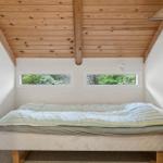 Schlafzimmer mit Holzdecke, zwei Fenstern und einem Bett mit Matratze.