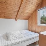 Schlafzimmer mit Holzwänden, Bett und Fenster zur Aussicht.