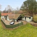 Haus mit Terrasse, Grill und Garten. Umgeben von Bäumen und Grasfläche.