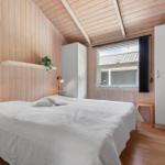 Schlafzimmer mit Holzwand, Bett, Fenster und Schränken.