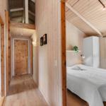 Schlafzimmer mit weißem Bett und Holzwand. Flur mit Tür und Wandbildern.