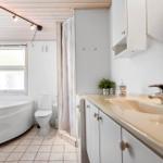 Badezimmer mit Badewanne, Toilette und Waschbecken mit Spiegel.